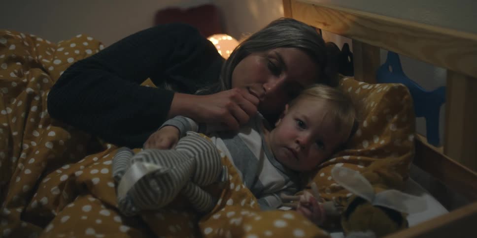 A mother is sleeping in bed with her son