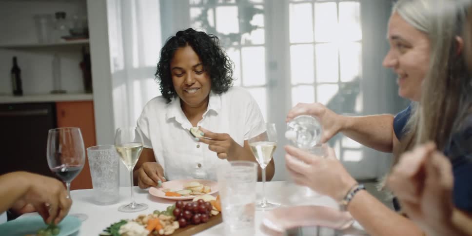 A group of women eat together at a dining table in a house during the day