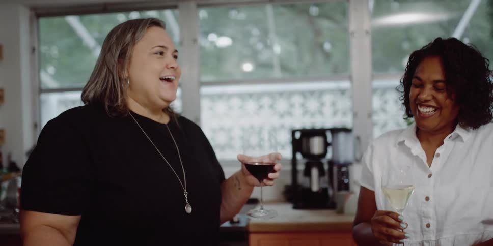 Group of happy friends drinking wine in the kitchen at home