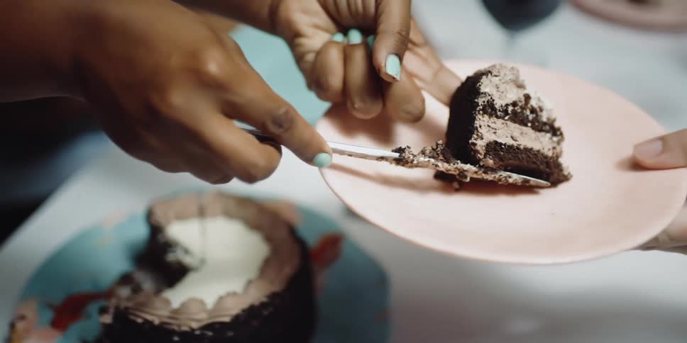 Woman serving a slice of cake on a plate in the dinner table