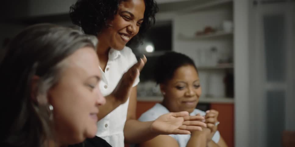 A group of women are sitting at a kitchen table setting up a meal
