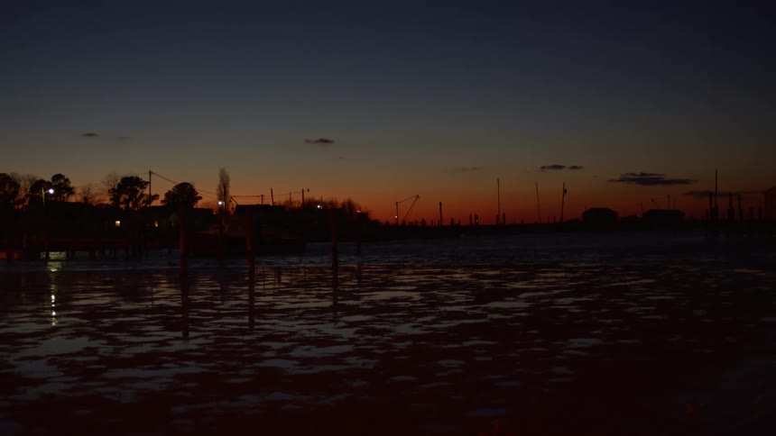Orange and blue sunset over a marina at low tide