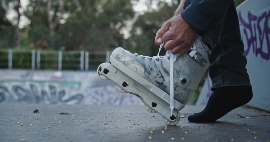 A man is putting on roller blades at a public park in spring