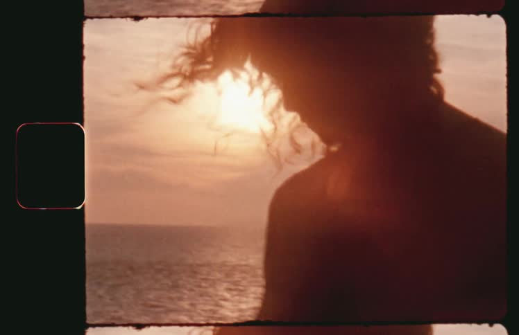 A woman is seen in silhouette against an evening sky over the water