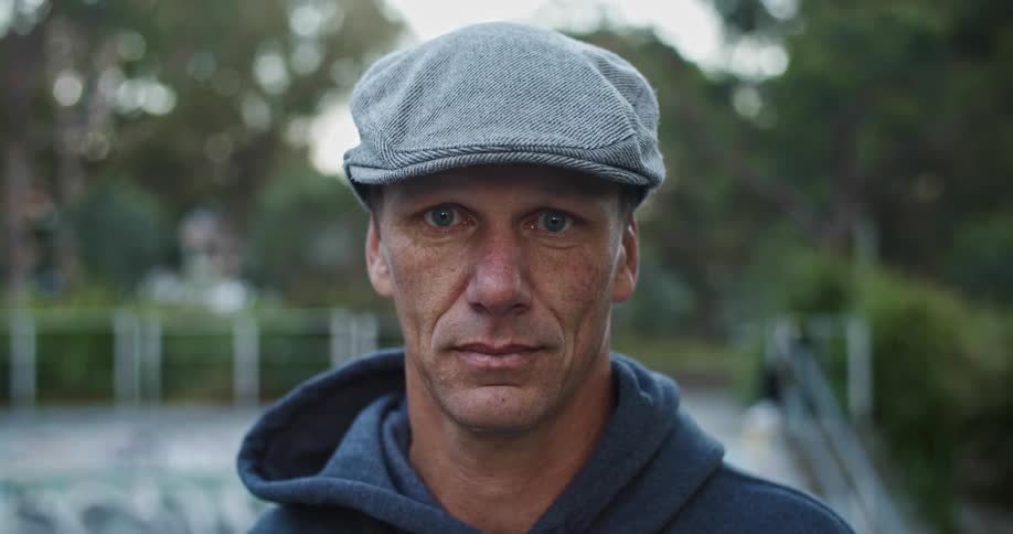 A man is standing outdoors and wearing a hat