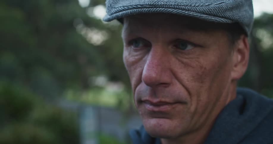 A man is wearing a hat and sitting outdoors in spring