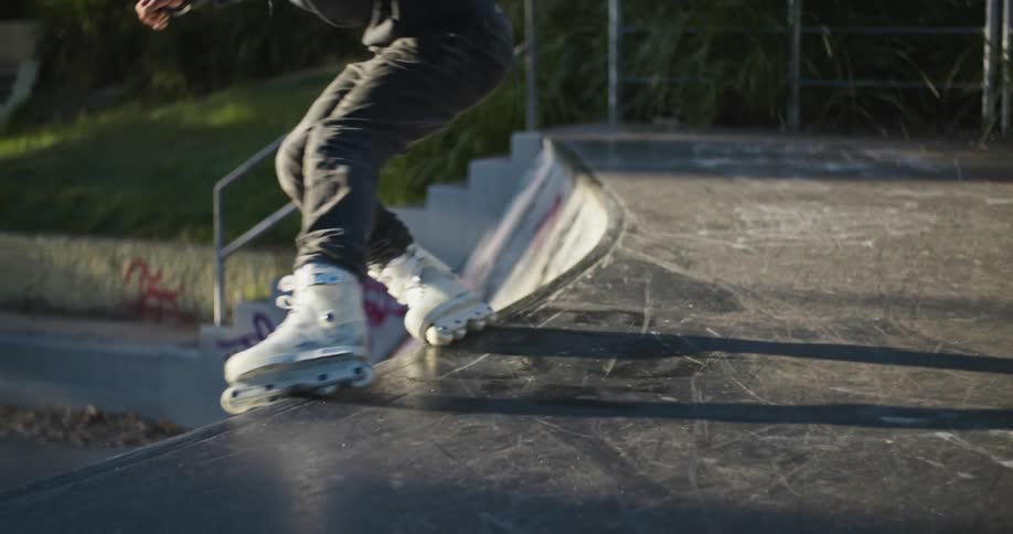 Roller blader skates up a ramp and then skates on the edge of it