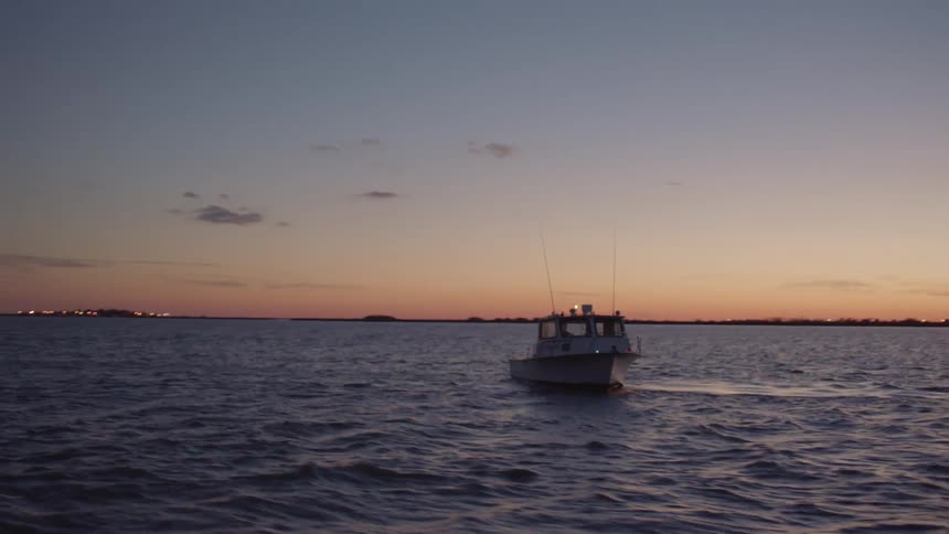A motor boat floating on calm water at sunset
