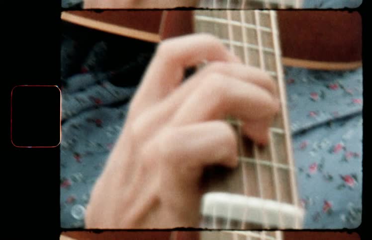 A filmstrip with a close up of a woman playing a guitar
