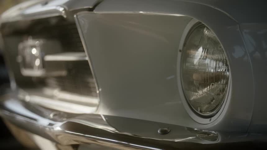 Car headlights and fender reflect sun light