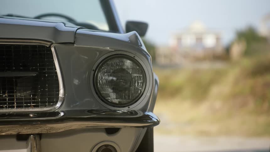 Headlight on an antique silver car parked outside during the day