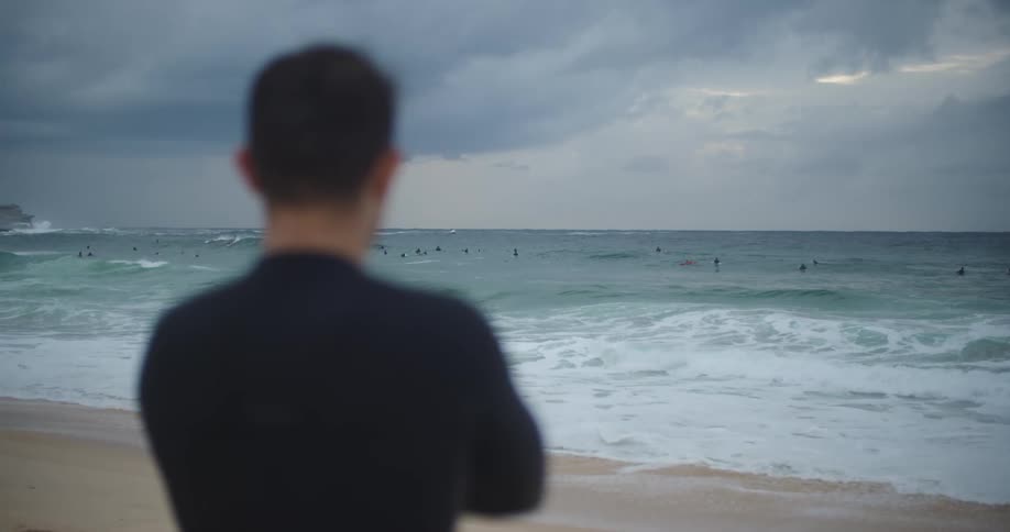 A man is standing on the beach at dusk