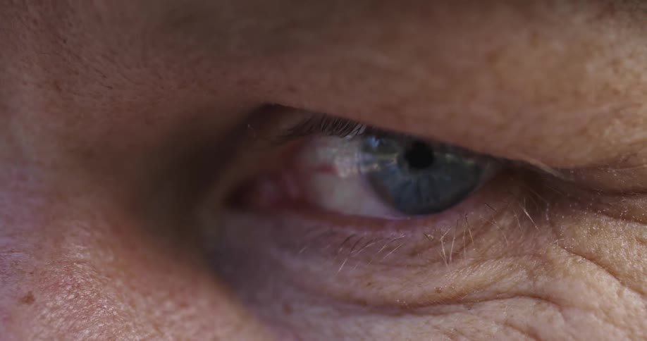 An extreme closeup of the eye of a man shows him blinking and looking around