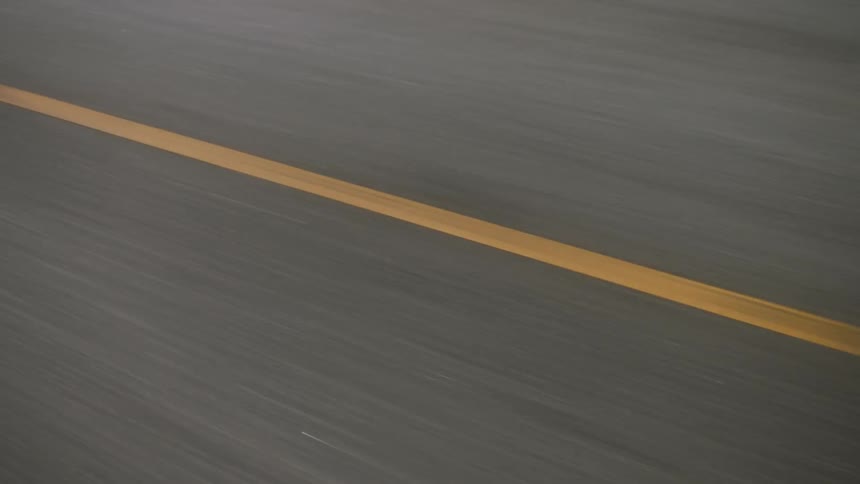A highway and the lane stripes are shown as someone moves along the road