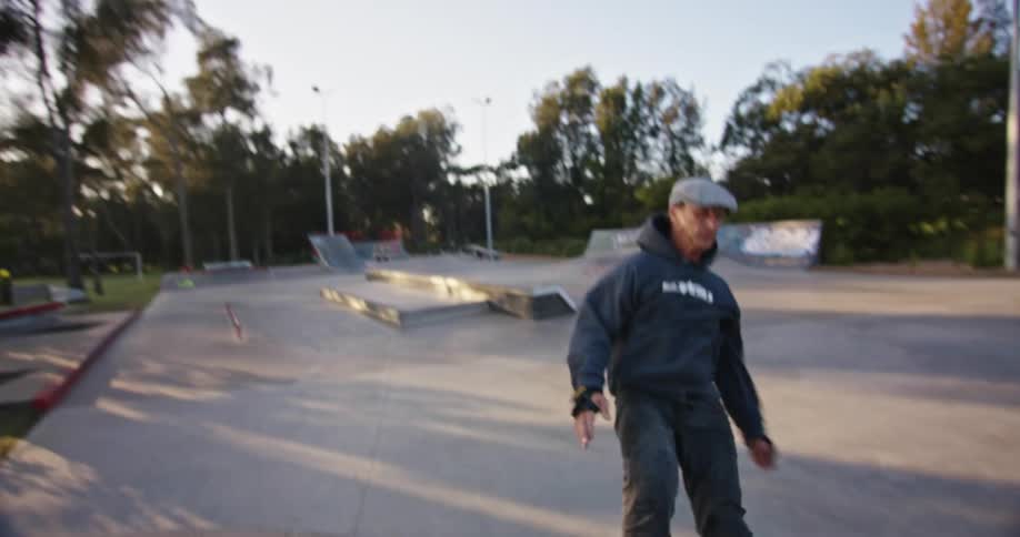 Man with roller skates jumping a concrete ramp in a park at sunset