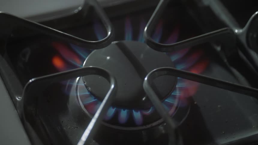A flame igniting on a gas burner of a stove