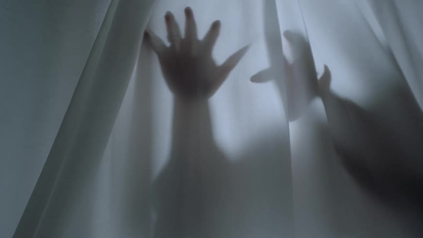 Shadow silhouette of a person sliding hands over a curtain