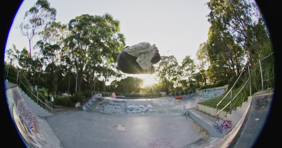 Man wearing skates jumps a ramp on a skating park at sunset
