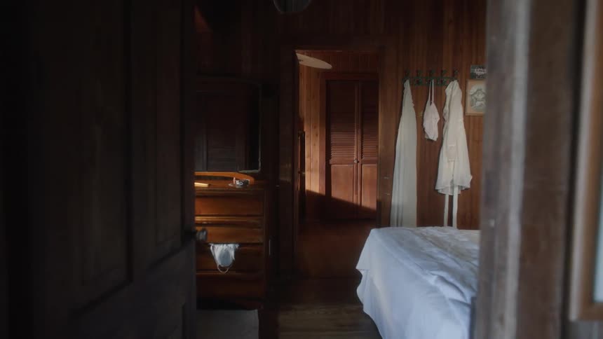 White bathrobes hang on the wall of a wood paneled bedroom