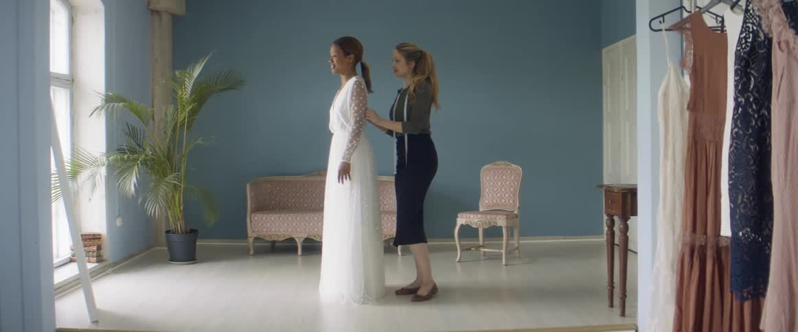 Two women are trying on dresses indoors