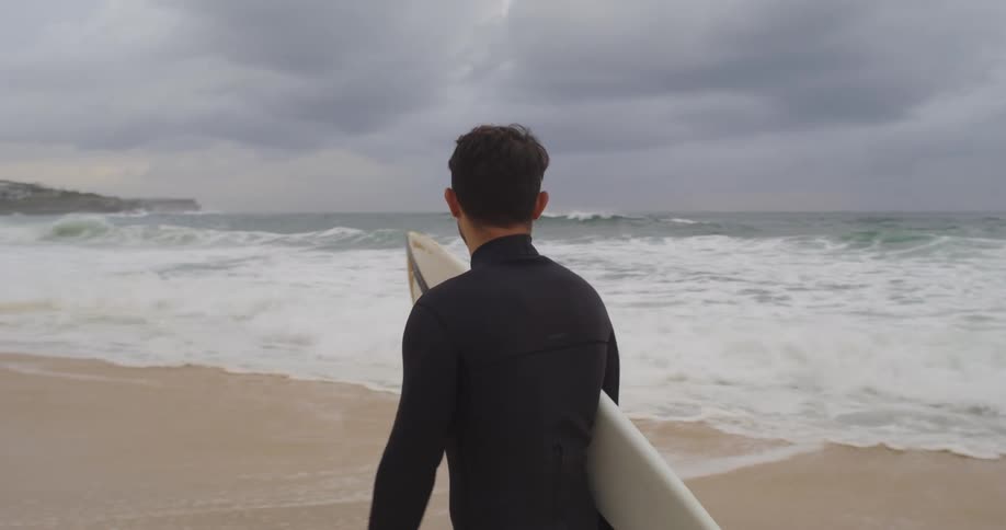 A man is surfing at the beach by the ocean