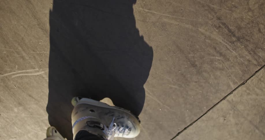 A person is standing on concrete and wearing roller blades