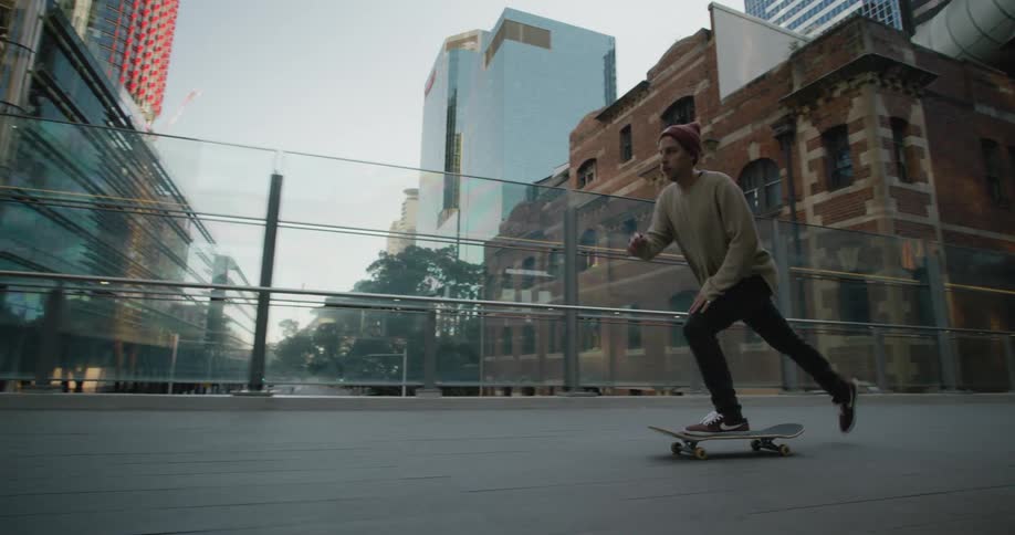 A man is skateboarding through a downtown city