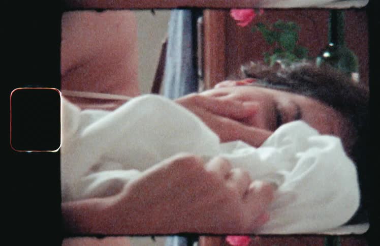 Woman laying in bed covers her face with her hands and bed sheets while laughing