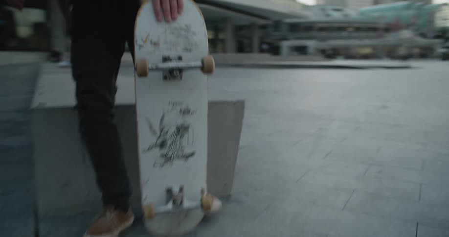 Young man stands up and starts riding a skateboard in the city
