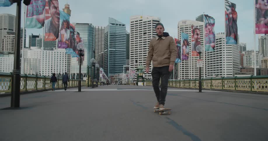 Young man riding a skateboard over a bridge near the city skyline