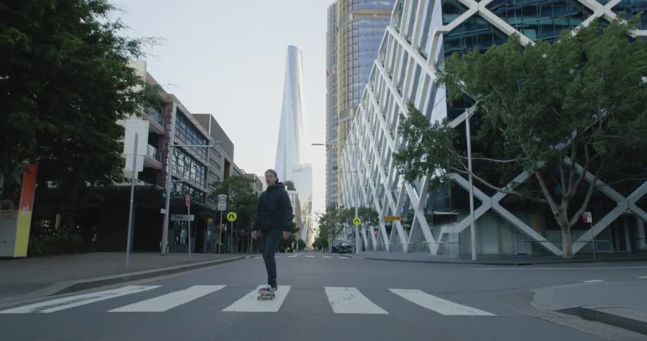 Young man driving a skateboard in the street of a city at morning