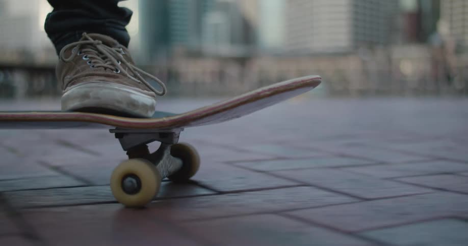 A person with sneakers in a city skating on a skateboard with buildings in the background