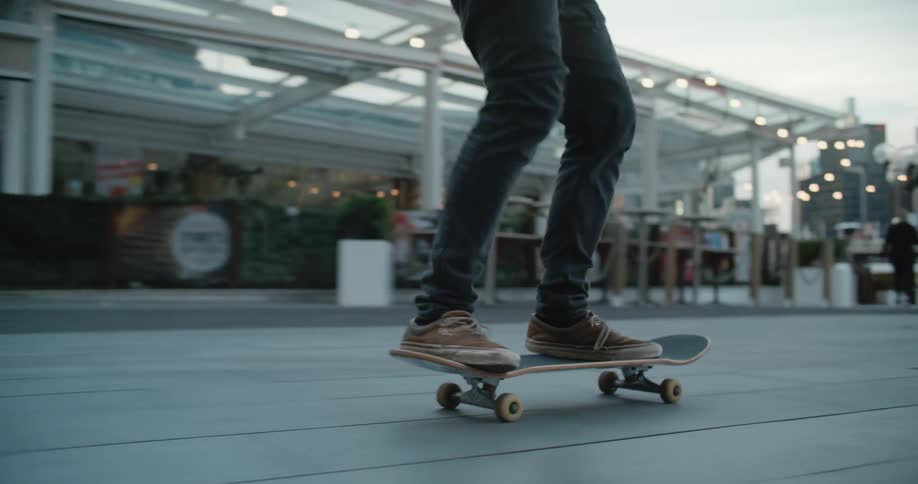 A man skateboards through a plaza outdoors in the evening