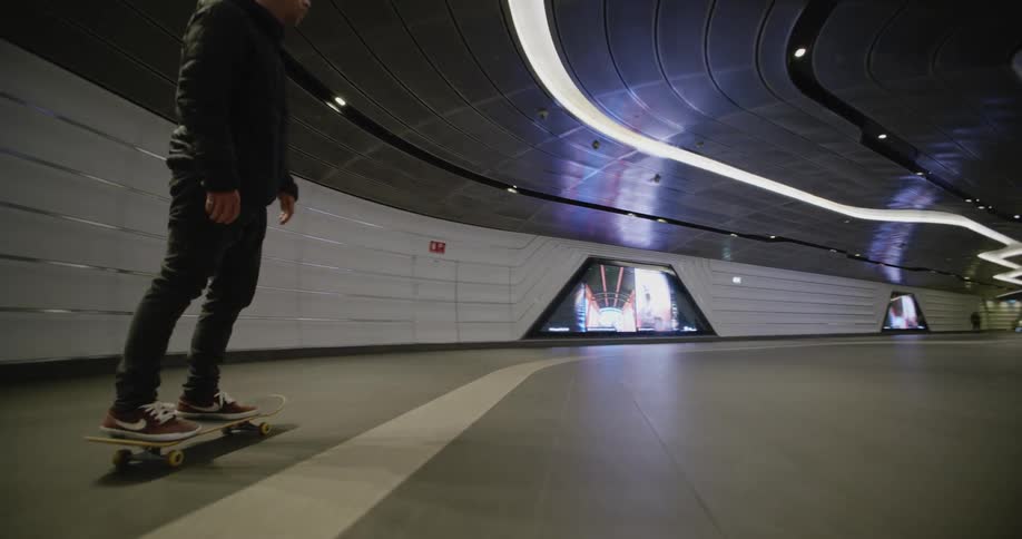 A man rides a skateboard through a building tunnel
