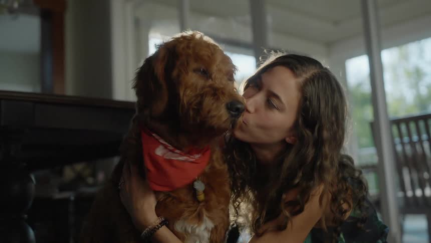 A girl is petting her dog and sitting indoors
