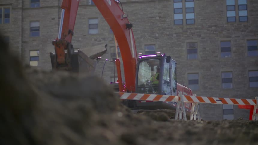 A construction vehicle lifts heavy debris on a work site