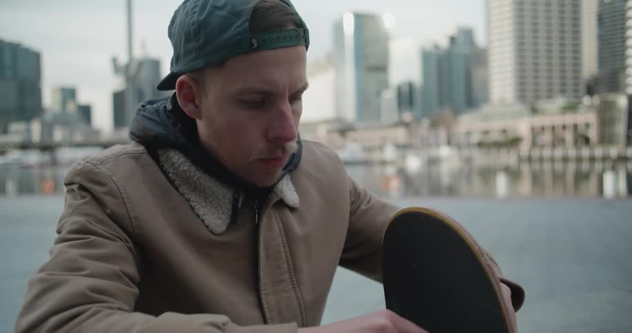 Man sits and tightens the wheels on his skateboard