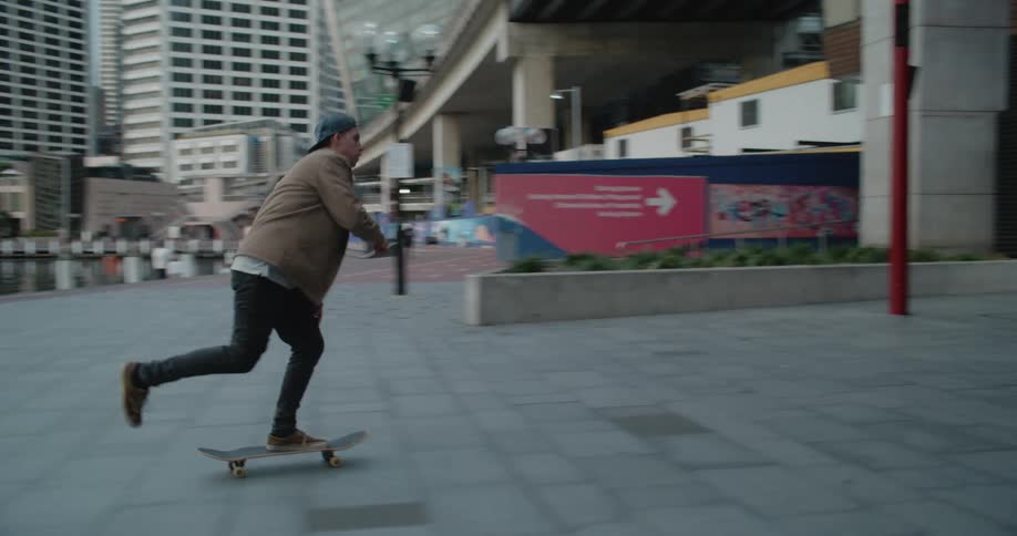 Young man riding a skateboard near the harbour in the city