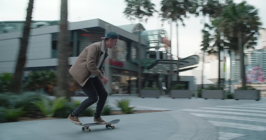 Teenager pushes himself along on a skateboard in the city and does a jump with it