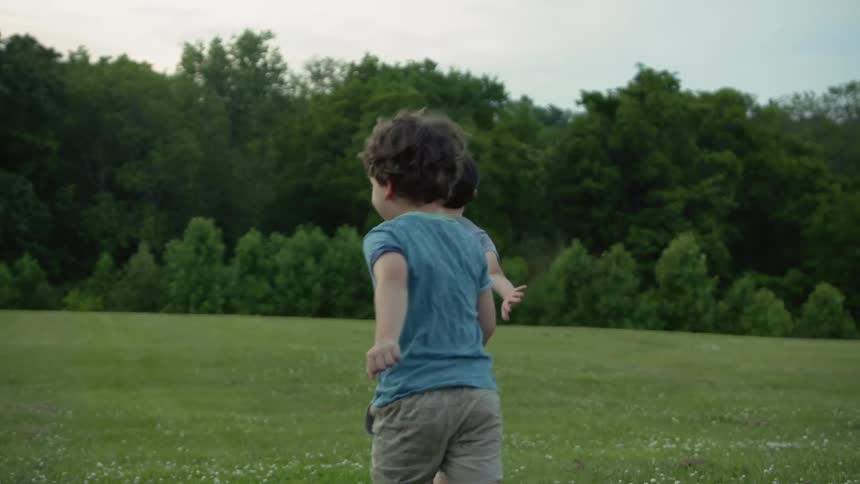 Two children are running and playing outdoors in spring