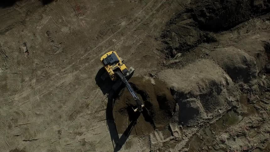 A tractor scoops up a large pile of dirt and dumps it out