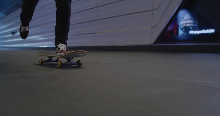 A person is skateboarding down a dark city sidewalk