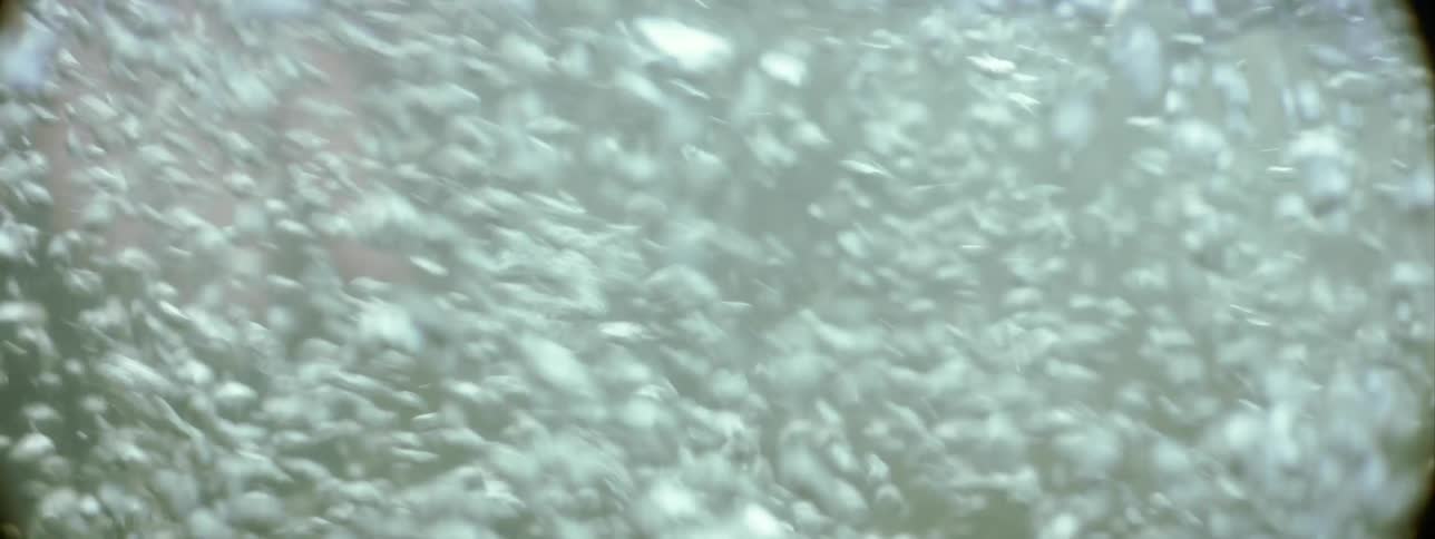 A person hands swimming underwater with bubbles