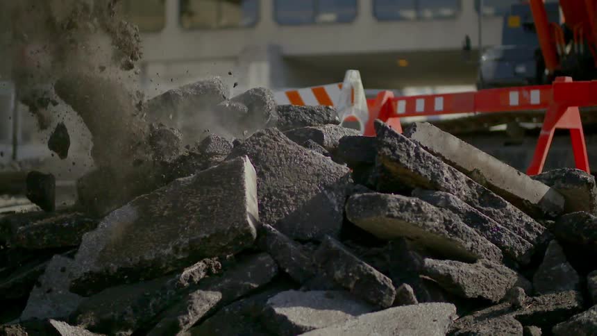 Heavy equipment bucket dropping some broken concrete onto a pile