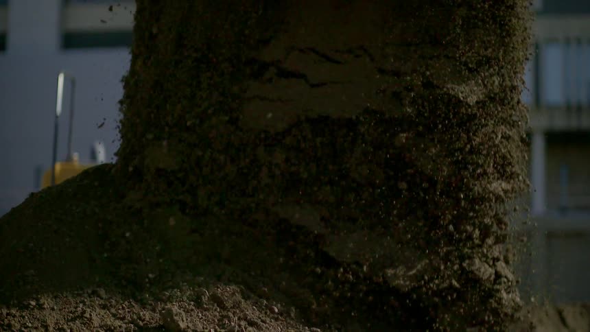 A tractor dumps a large pile of sand out