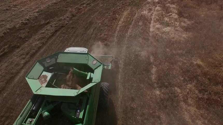 A farm tractor is working a large field