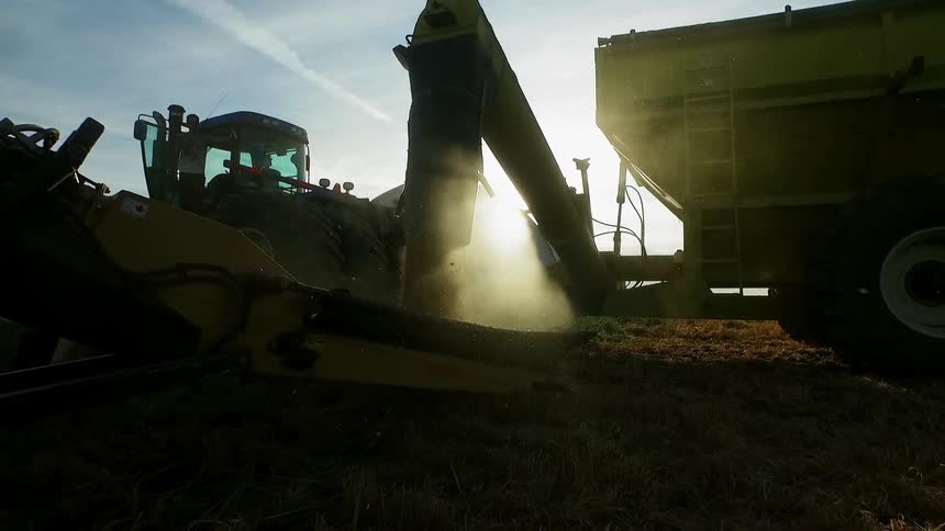 Large farm equipment is working a field on a cloudy day