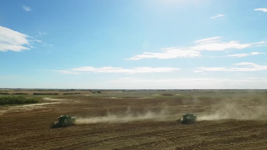 Two large tractors work farmland on a sunny day