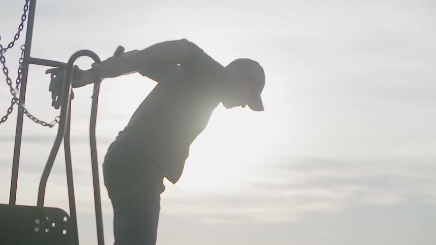 A man climbs down steps and jumps down onto grass in a field