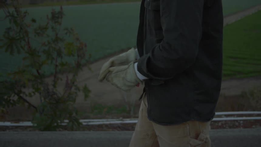 A man walking outdoors and putting on gloves